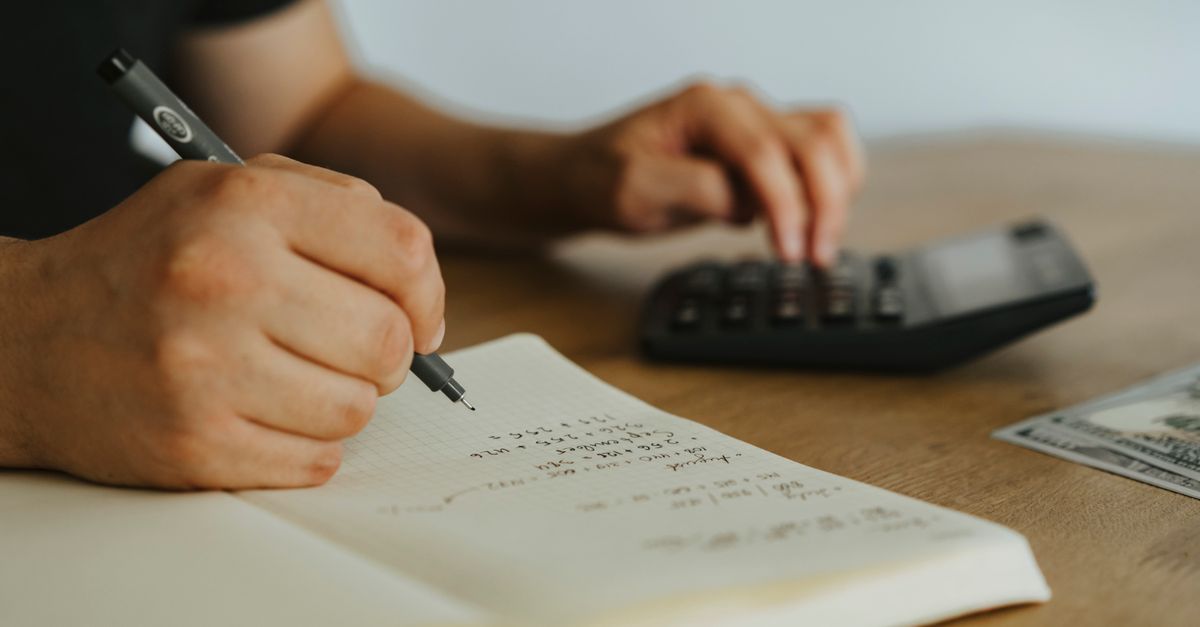 Close-up of hands writing calculations in a notebook with a calculator, focused on budgeting or financial work. — illustrating create a reciept