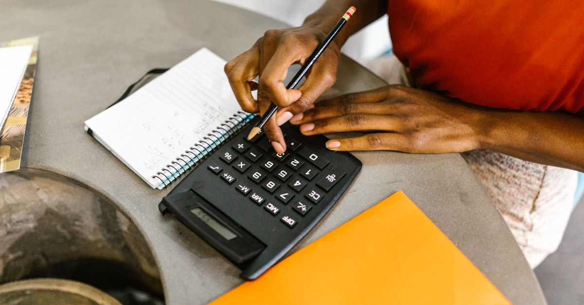 An African American woman using a calculator and notepad for budgeting. — illustrating expenses reciept