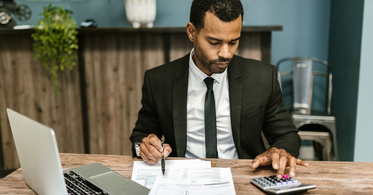 A focused businessman works with a calculator and documents in a modern office. — illustrating expensesrecipt