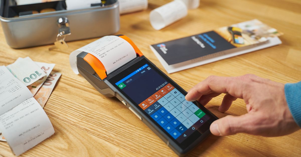 Person using a digital payment terminal on a wooden desk with cash and receipts visible. — illustrating express receipt
