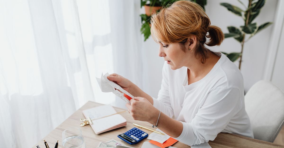 Woman sitting at a desk managing finances with a calculator and paper receipts in an office setting. — illustrating express receipts
