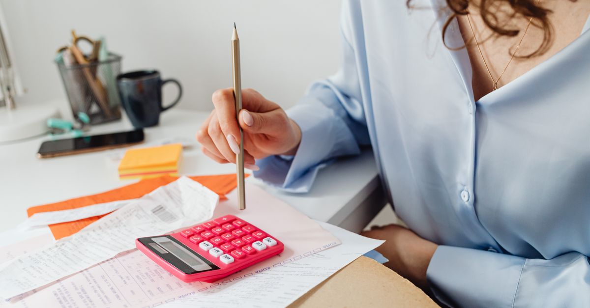 A woman is calculating expenses using a calculator and papers at her desk. — illustrating gas receipts