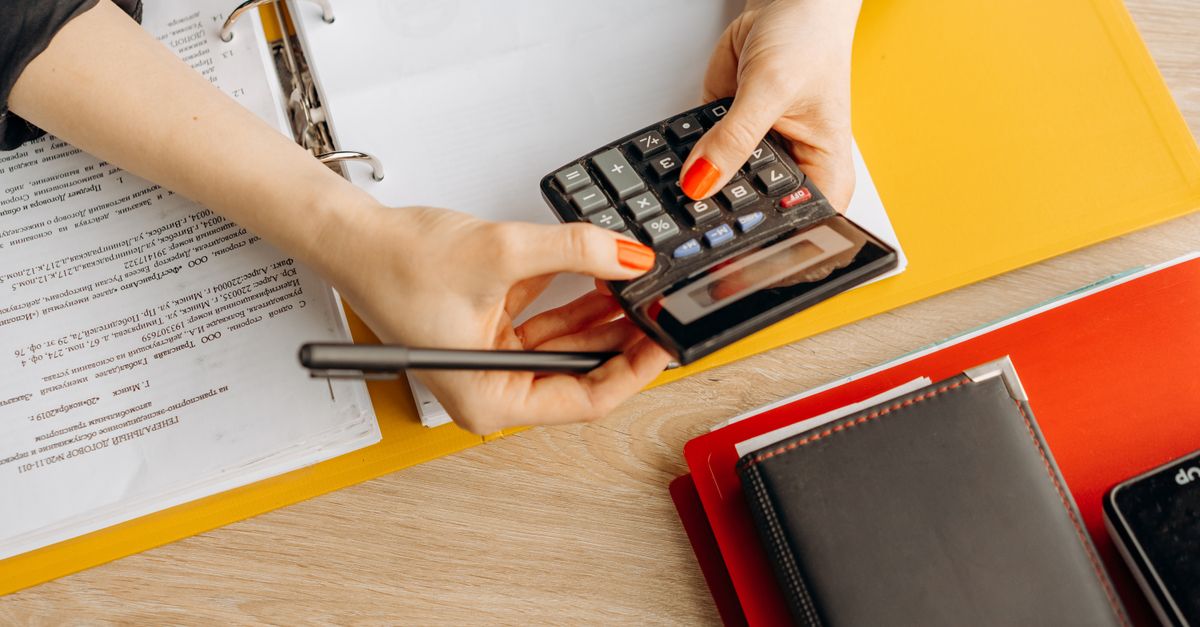 Hands using a calculator at a desk with documents and folders, ideal for finance or accounting themes. — illustrating generate receipts