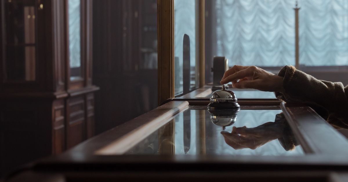 A hand pressing a service bell on an elegant wooden hotel desk, creating a classic atmosphere. — illustrating hotel receipt