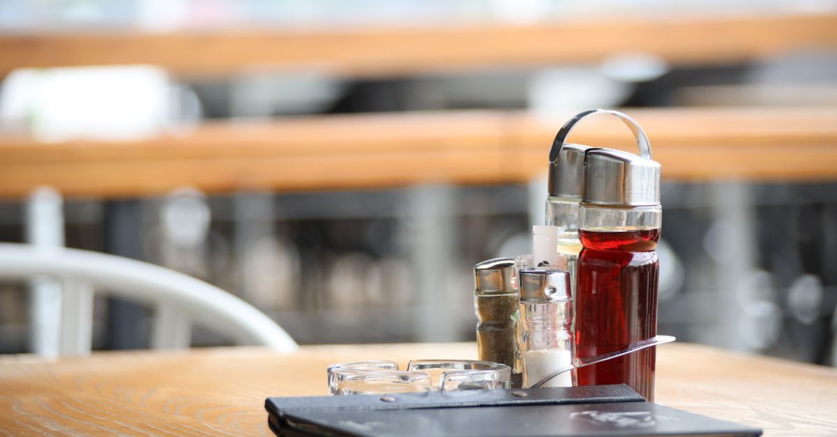 Close-up of a restaurant table with condiments and a menu, ideal for dining themes. — illustrating restaurant receipt template