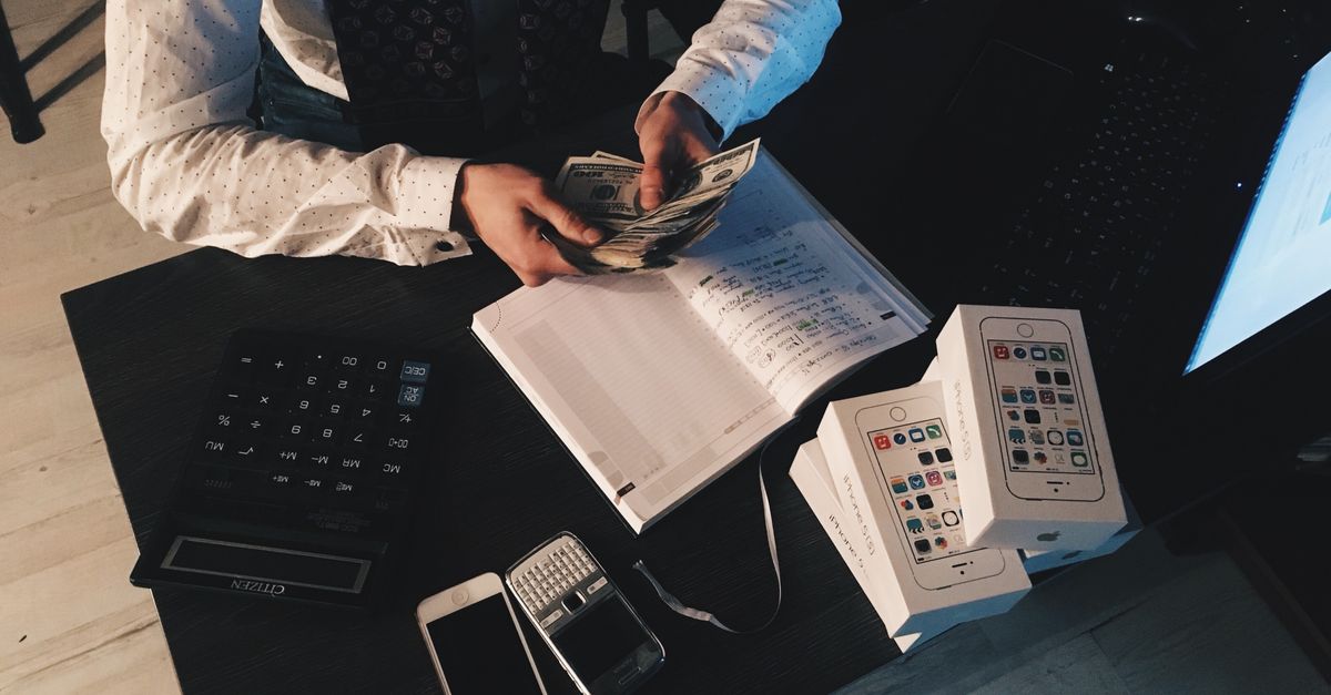 Businessman organizing finances with tech devices and cash on desk. — illustrating reciept maker
