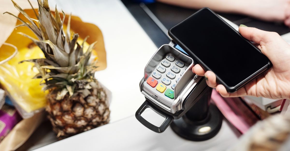 Close-up of a customer using a smartphone for contactless payment at a retail checkout with a pineapple on the counter. — illustrating make receipt walmart