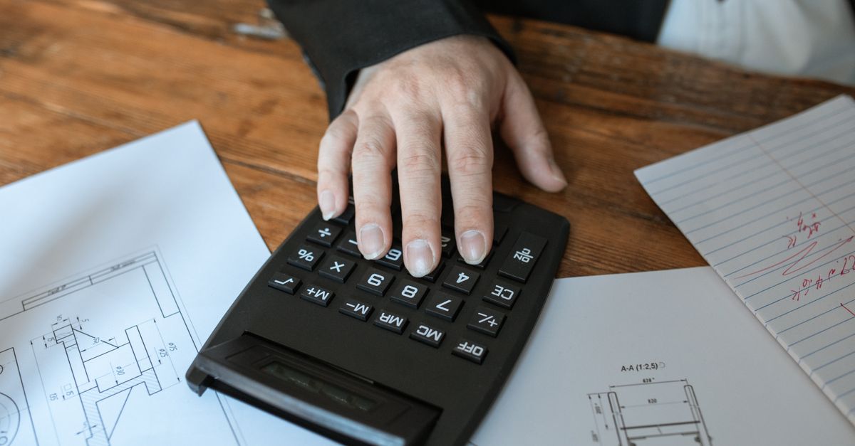 Hand using calculator for architectural calculations on blueprints. — illustrating expenses receipt