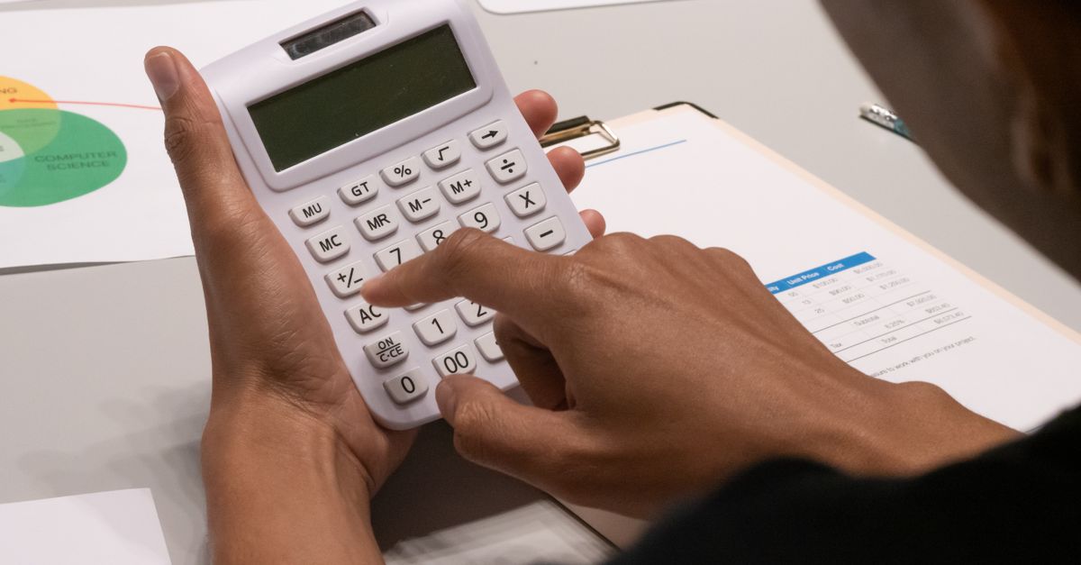 Focused image of a person using a calculator amidst financial documents and charts. — illustrating expensesreceipt