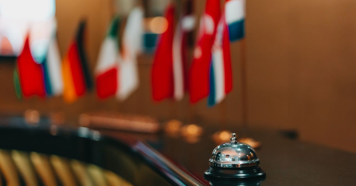 Sophisticated hotel lobby with a reception bell and array of international flags in focus. — illustrating airbnb receipt generator