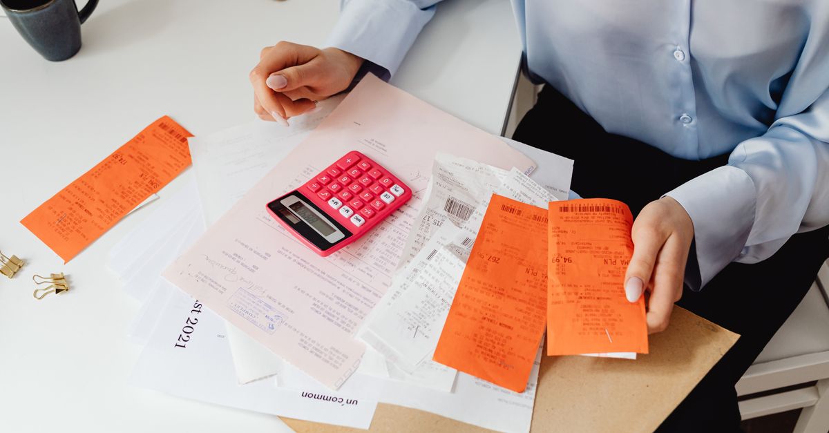 A woman reviews receipts and calculates expenses at a desk with a pink calculator. — illustrating receipt creator online