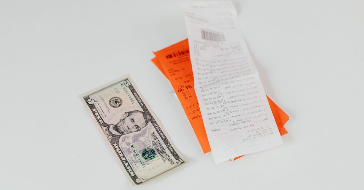 Close-up of a five-dollar bill next to shopping receipts on a white background, ideal for finance and retail themes. — illustrating receipt making