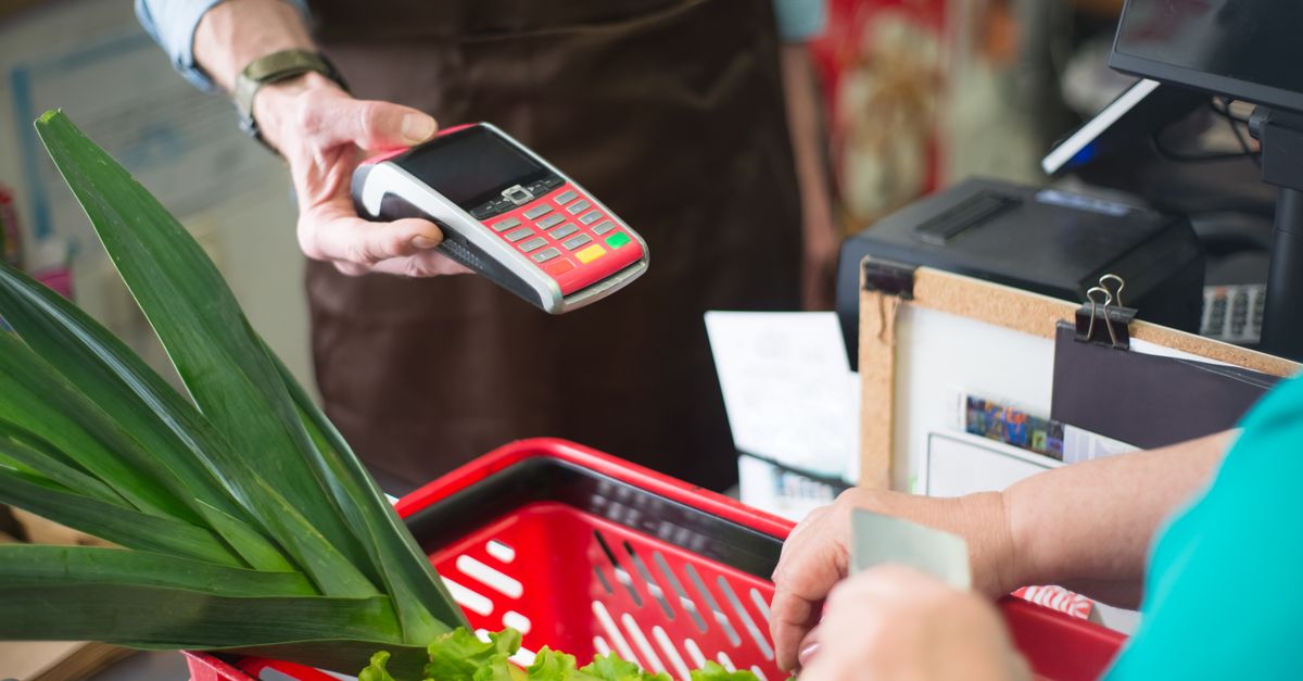 A customer using a contactless payment method at a grocery store checkout with fresh produce. — illustrating store recite