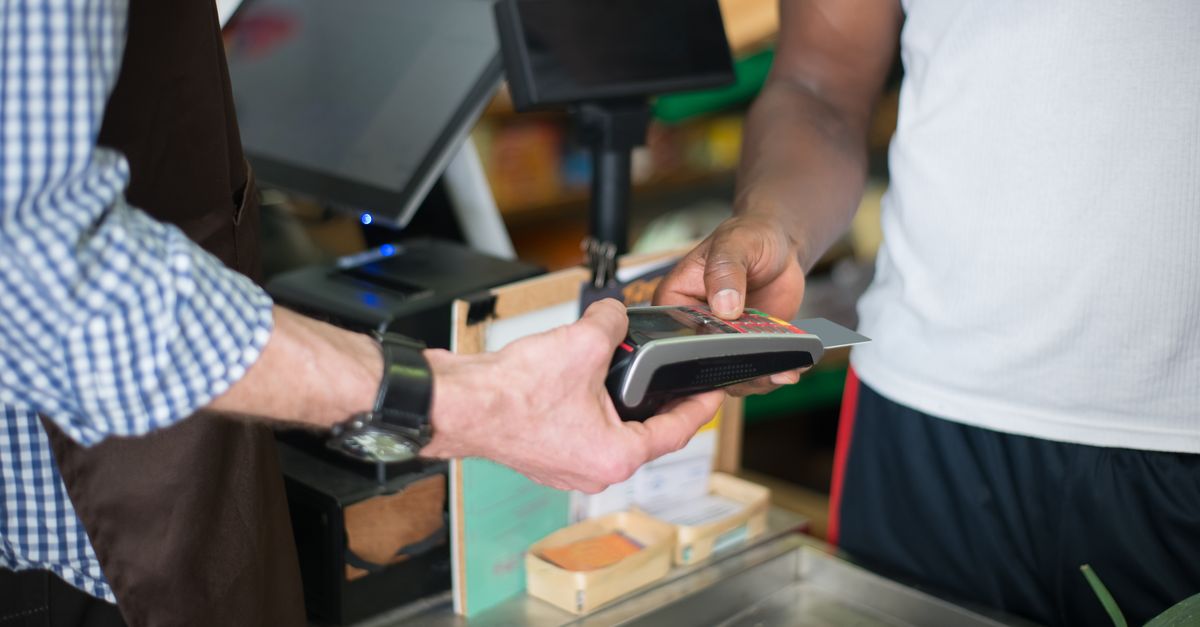A customer making a payment with a credit card at a store checkout counter using a card reader. — illustrating store recite