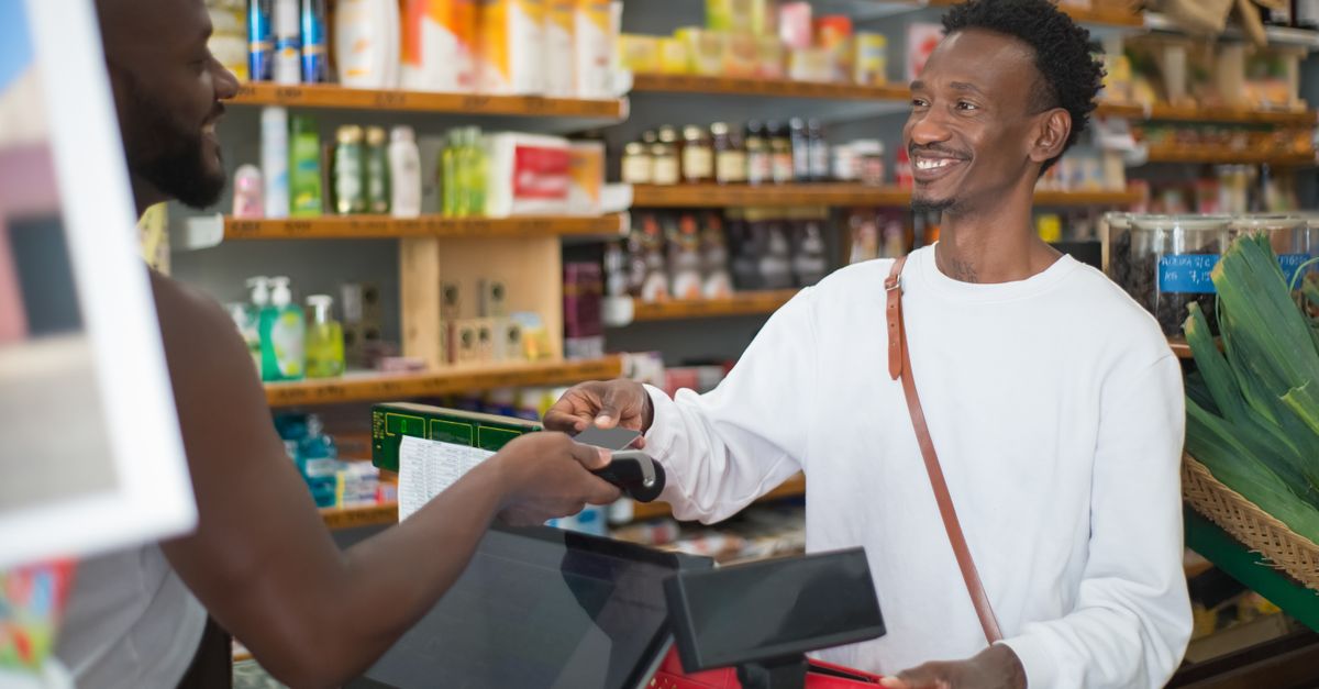 Two men engaging in a friendly transaction at a grocery store counter, emphasizing shopping and communication. — illustrating store recite