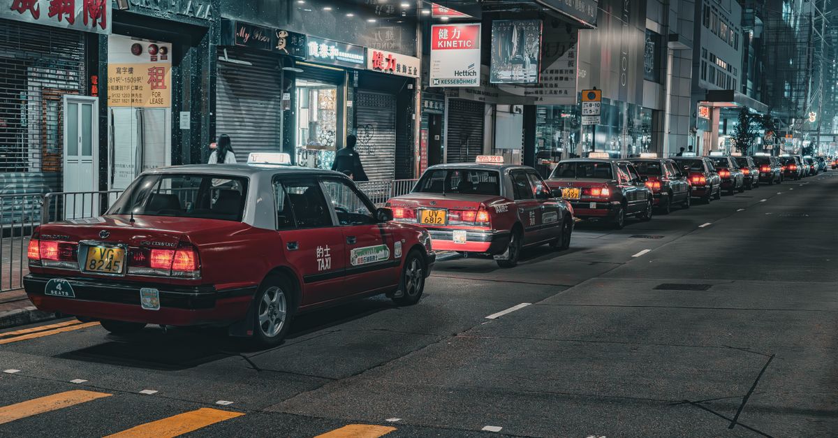 A street in Hong Kong bustling with red taxis at night, capturing urban life and city lights. — illustrating taxi cab receipt template