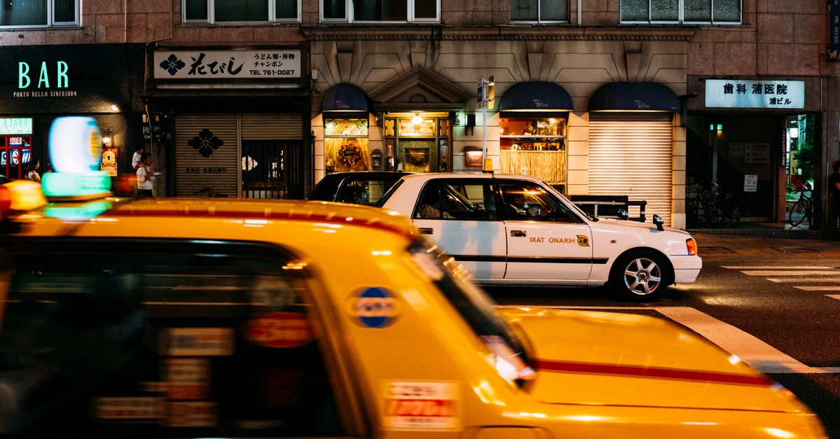 Dynamic Tokyo street scene featuring yellow taxis and illuminated storefronts at night. — illustrating taxi cab receipt template