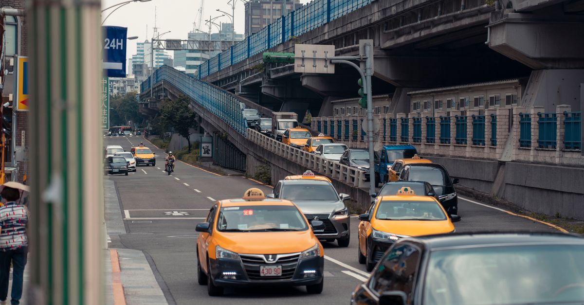 Yellow taxis and vehicles navigating an urban street under an overpass. — illustrating taxi receipt